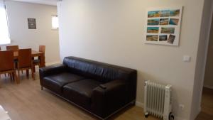 a black leather couch in a living room with a table at Fish house Sesimbra in Sesimbra