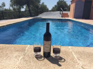 una botella de vino y dos copas junto a la piscina en Belvilla by OYO Casa Guzm n en Árchez