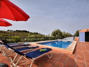 une terrasse avec une piscine et un parasol rouge dans l'établissement Belvilla by OYO Casa Guzm n, à Árchez