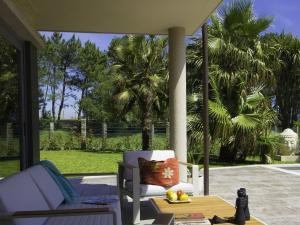 un porche con una silla, una mesa y palmeras en Beautiful cottage nicely furnished in the valley city Gwent en Pontevedra