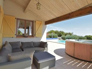 une terrasse avec un canapé et un bain à remous dans l'établissement Villa with heated pool and hot tub, à Vélieux