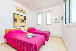 two beds in a room with pink sheets at Villa Constantina in Protaras