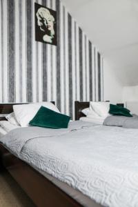two beds with green pillows in a bedroom at Hotel Złotogórski in Kościelec