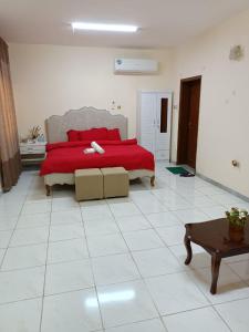 a bedroom with a bed with a red blanket and a table at Residence villa 106 in Al Ain