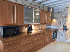 a kitchen with wooden cabinets and a microwave at GITE D'HAUTEVESNES in Hautevesnes