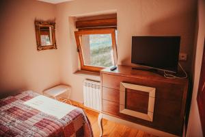 um quarto com uma televisão numa cómoda com uma cama em El reguero de Villamarín em Villamarin