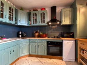 a kitchen with blue cabinets and a stove top oven at Quiet villa with private pool in Caunes-Minervois