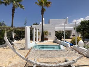 a house with a swimming pool and palm trees at Belvilla by OYO Can Pep Rustico in Sant Miquel de Balansat