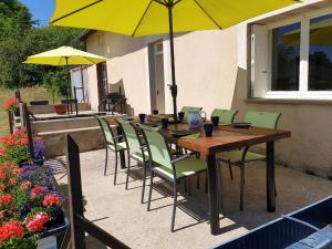 - une table en bois avec des chaises et un parasol sur la terrasse dans l'établissement Comfortable holiday home with pool, à Grury