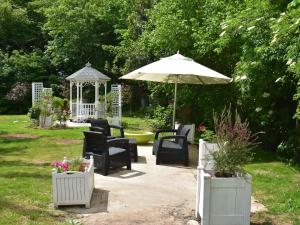 een patio met stoelen, een parasol en een prieel bij Superb holiday home near the beach in Quinéville