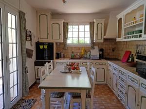 una cucina con armadi bianchi e un tavolo con frutta di Charming house with private pool a La Tour-sur-Orb