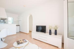 a white living room with a tv and a table at Apartamentos Annabel's 2-3 HABITACIONES in Cala Galdana