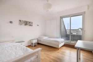 ein weißes Schlafzimmer mit einem Bett und einem Fenster in der Unterkunft Vacances pour 6 à 400m de la plage à Sarzeau in Sarzeau