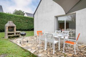 eine Terrasse mit einem Tisch, Stühlen und einem Grill in der Unterkunft Vacances pour 6 à 400m de la plage à Sarzeau in Sarzeau