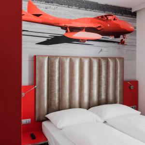 a bedroom with a red airplane painting on the wall at Amedia Express Graz Airport, Trademark Collection by Wyndham in Feldkirchen bei Graz