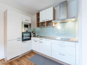 a white kitchen with wooden floors and white cabinets at Apartment to the Zillertal near F gen in Bruck am Ziller