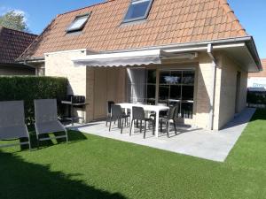 un patio con mesa y sillas frente a una casa en Cosy Holiday Home near Westhoek, en De Panne