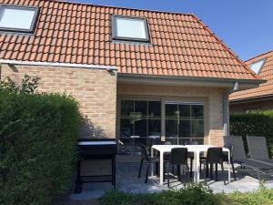 a patio with a table and chairs and a piano at Cosy Holiday Home near Westhoek in De Panne