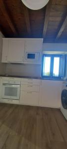 cocina con armarios blancos y microondas y 2 ventanas en Casa vacacional La Belluga, en Canales