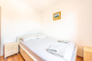 ein Schlafzimmer mit einem Bett mit weißer Bettwäsche und einem Bild an der Wand in der Unterkunft Apartment Damir in Novalja