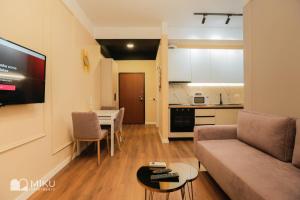 a living room with a couch and a table and a kitchen at Miku Apartment - Perfect 1Bedroom At Komuna e Parisit in Tirana