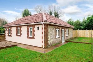 une petite maison en brique avec une pelouse dans l'établissement The Lodge, à Coltishall