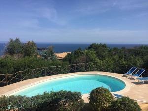 a swimming pool with two chairs and the ocean at Villa Turchese - Key to Villas in Costa Paradiso