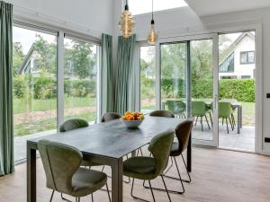 comedor con mesa, sillas y ventanas de cristal en Bungalow in Texel near National Park Dunes, en Westermient