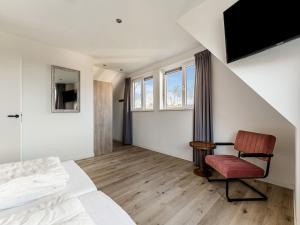 a bedroom with a bed and a chair and a window at Alluring Holiday Home in De Koog Texel with Infrared Sauna in Westermient
