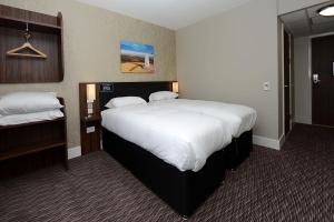 a hotel room with a large bed with white sheets at Kings Highway, Derby by Marston's Inns in Derby