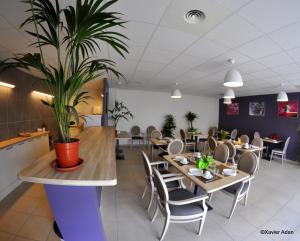 a restaurant with tables and chairs and a potted plant at Douce France in Cuxac-dʼAude