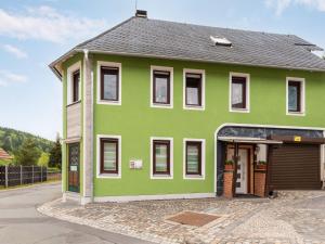 a green house with a black roof at Bright apartment in a district of Ilmenau in Stützerbach