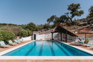 a swimming pool with lounge chairs and a resort at Finca El Almendrillo in Iznájar