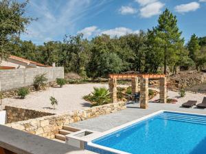 a swimming pool in a yard with a stone wall at Wonderful villa in Ferreira do Zezere with private pool in Almogade