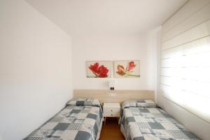 カンブリルスにあるApartamento Badiaの白い壁のベッドルーム1室(ベッド2台付)