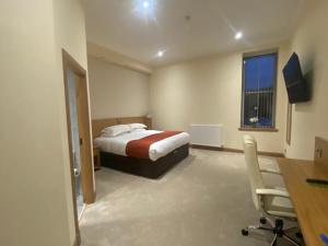 a bedroom with a bed and a desk and a window at The City Hotel in Dunfermline