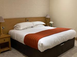 a hotel room with a bed, desk, and nightstand at The City Hotel in Dunfermline