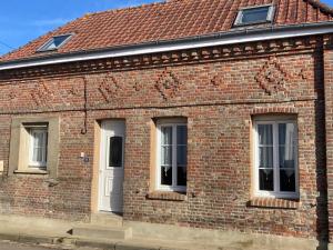 a brick building with three windows and a white door at L'Aube en Somme in Millencourt-en-Ponthieu