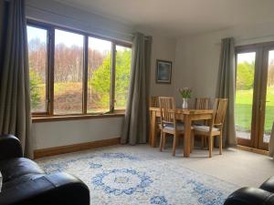 a living room with a table and chairs and windows at Arisaig Holiday Apartment in Arisaig