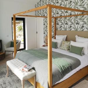 - une chambre avec un lit à baldaquin et une chaise dans l'établissement Quinta das Levadas - Country House & Nature, à Alvoco das Várzeas