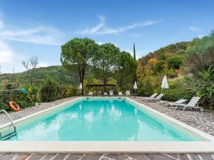 una piscina con 2 sillas, una mesa y árboles en Captivating Apartment in Assisi with Swimming Pool, en Asís