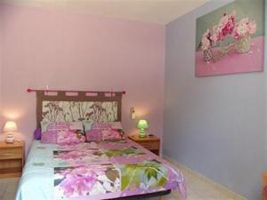 ein Schlafzimmer mit einem Bett mit rosa Blumen drauf in der Unterkunft L'Oliveraie in La Motte-dʼAigues