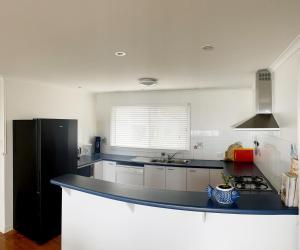 a kitchen with a black refrigerator and a counter at Bower by the Sea in Penneshaw