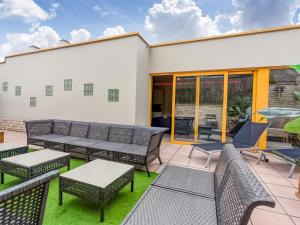 eine Terrasse mit Tischen, Stühlen und Fenstern in der Unterkunft Lush holiday home with spa and wellness in Avelgem