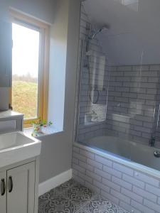 La salle de bains est pourvue d'une baignoire, d'un lavabo et d'une fenêtre. dans l'établissement Arisaig Holiday Apartment, à Arisaig