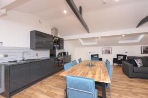 a kitchen and dining room with a wooden table and blue chairs at Concert Square Apartments By Happy Days in Liverpool