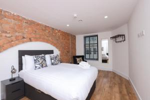 una camera da letto con un muro di mattoni e un grande letto di Concert Square Apartments By Happy Days a Liverpool