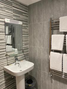 bagno con lavandino, specchio e asciugamani di The City Hotel a Dunfermline