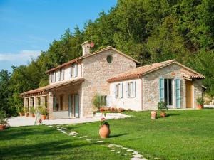 uma grande casa de pedra com um jardim relvado em Belvilla by OYO Ca Luigi em Acqualagna