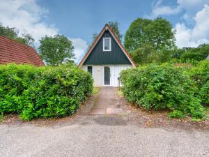 uma casa branca com um telhado preto e dois arbustos em Nice holiday home in Gramsbergen on family park em Gramsbergen